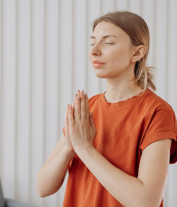 Woman in a calming yoga pose in a dimly lit room, suggesting relaxation and sleep.